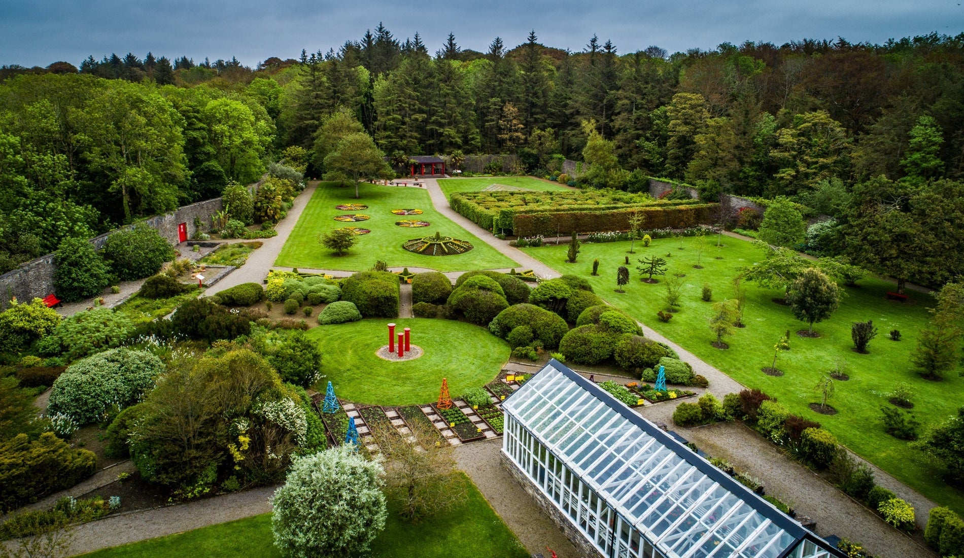 An aerial view across a walled garden with a glasshouse in the foreground