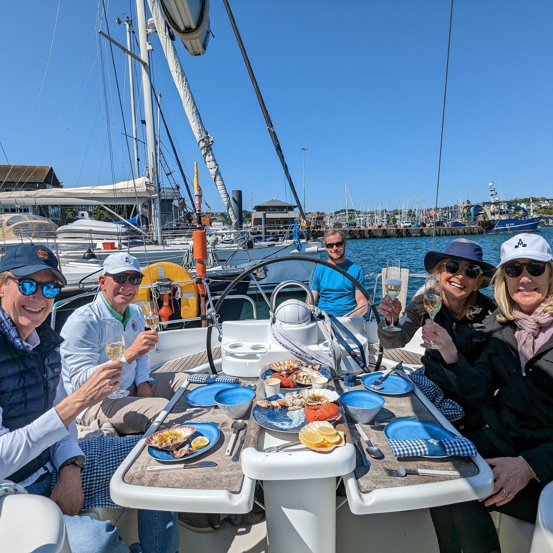 Four people on a yacht sitting around a small table with food platters