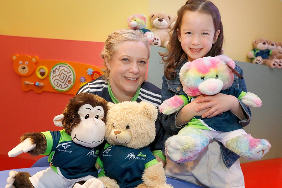 A smiling woman and child holding cuddly toys.