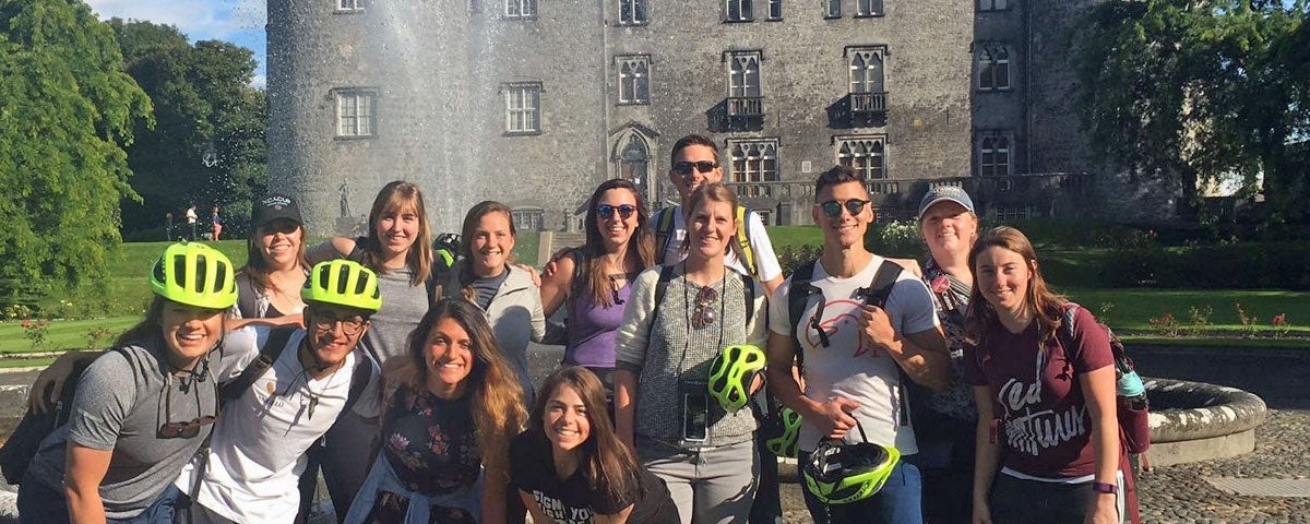 A group of cyclists on a tour with Kilkenny Castle in the background