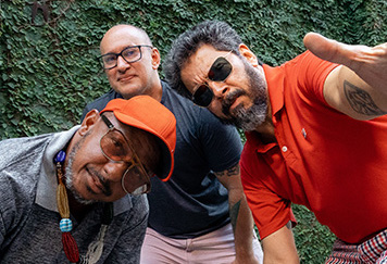 3 men, slightly crouching down, looking with attitude down the lens of the camera.