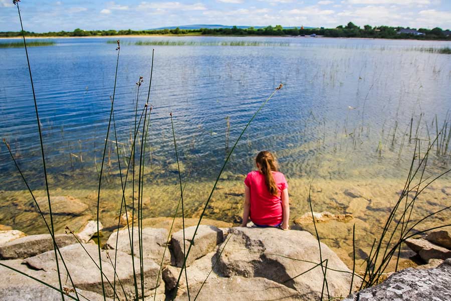 Girl sitting on the edge of a lake