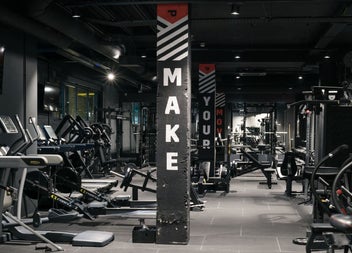 A spacious industrial style gym floor fitted with strength and cardio equipment
