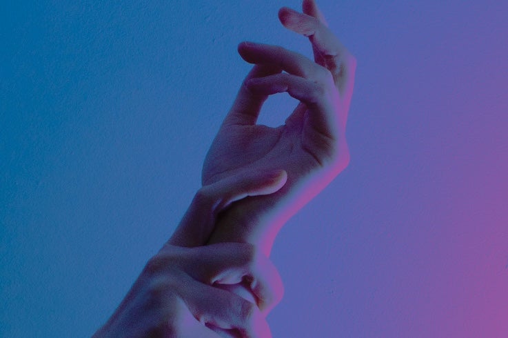 A pair of hands held up against plain blue, purple background.