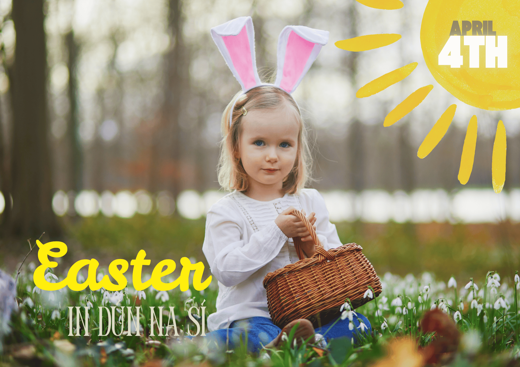 A young girl with rabbit ears headband holding a wicker basket seated on the ground with small white flowers.