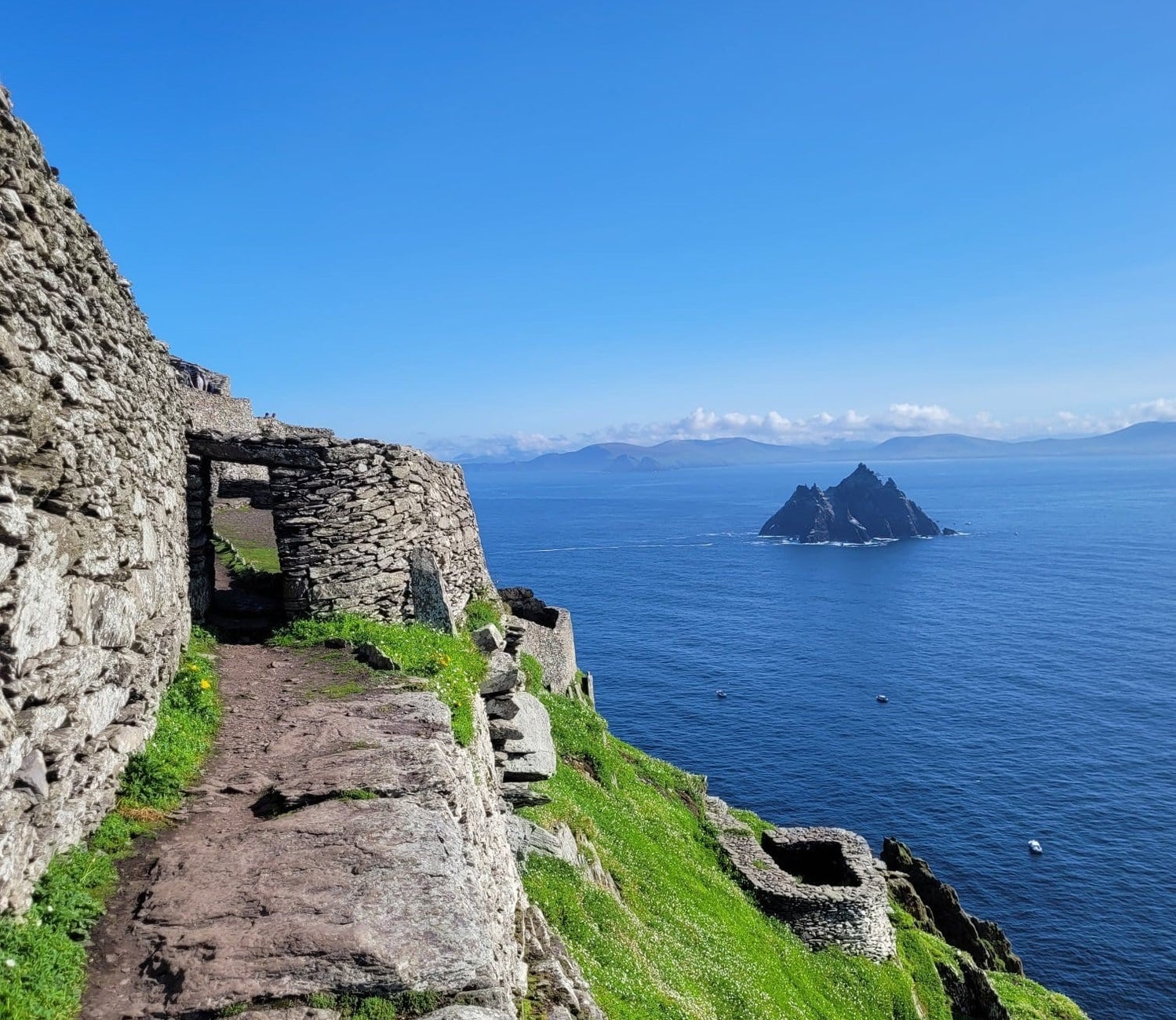 Stone and grass pathway on an island in the sea with another island in the background