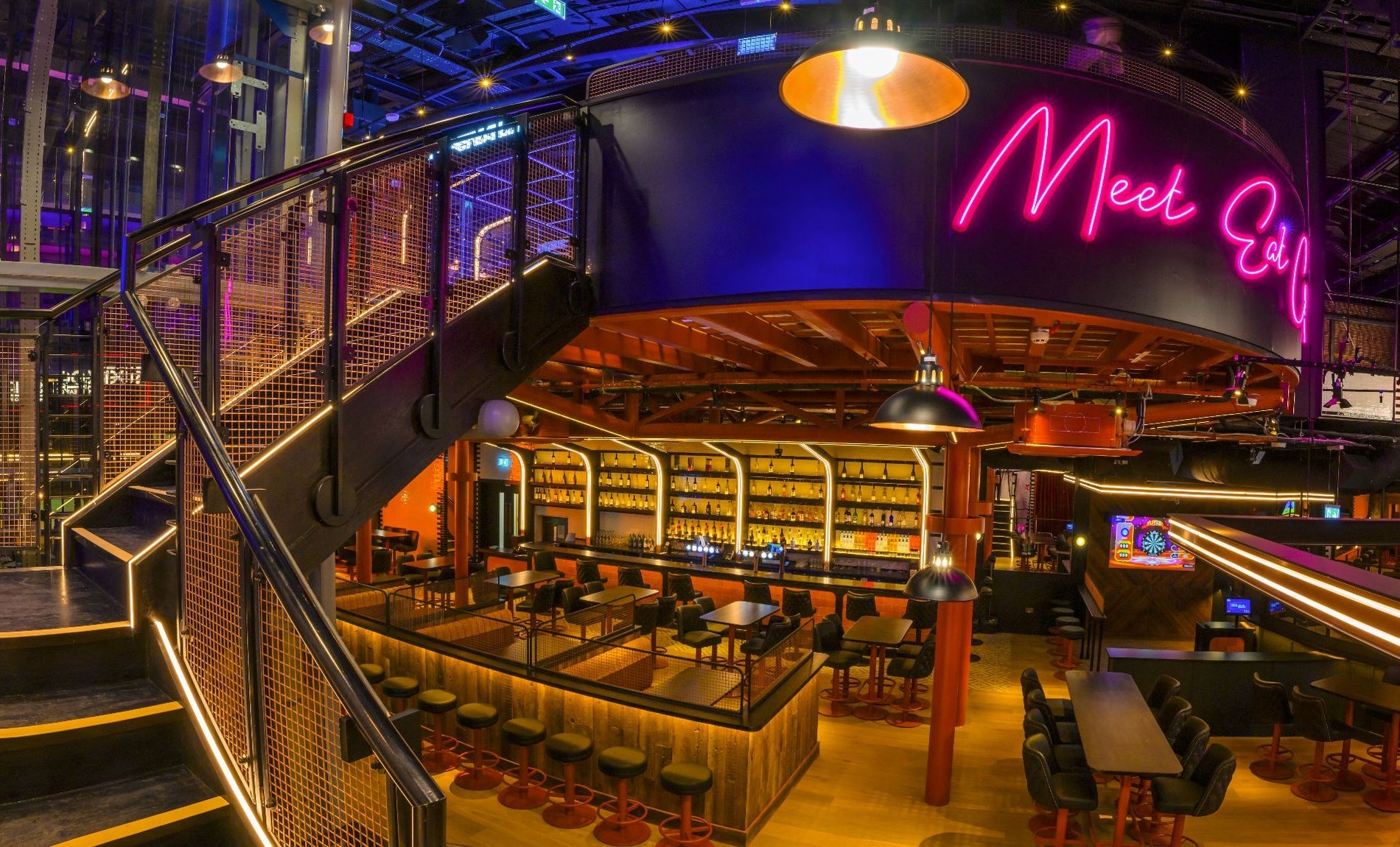 Bar area with neon lights over the counter and steps leading to an upstairs level