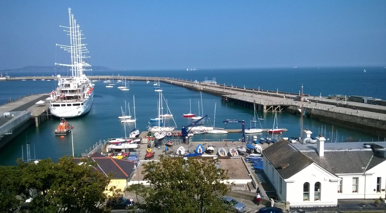 A view of a harbour with small boats and one large ship with tall masts