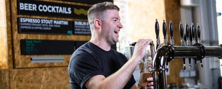 A laughing barman pours a pint of Guinness