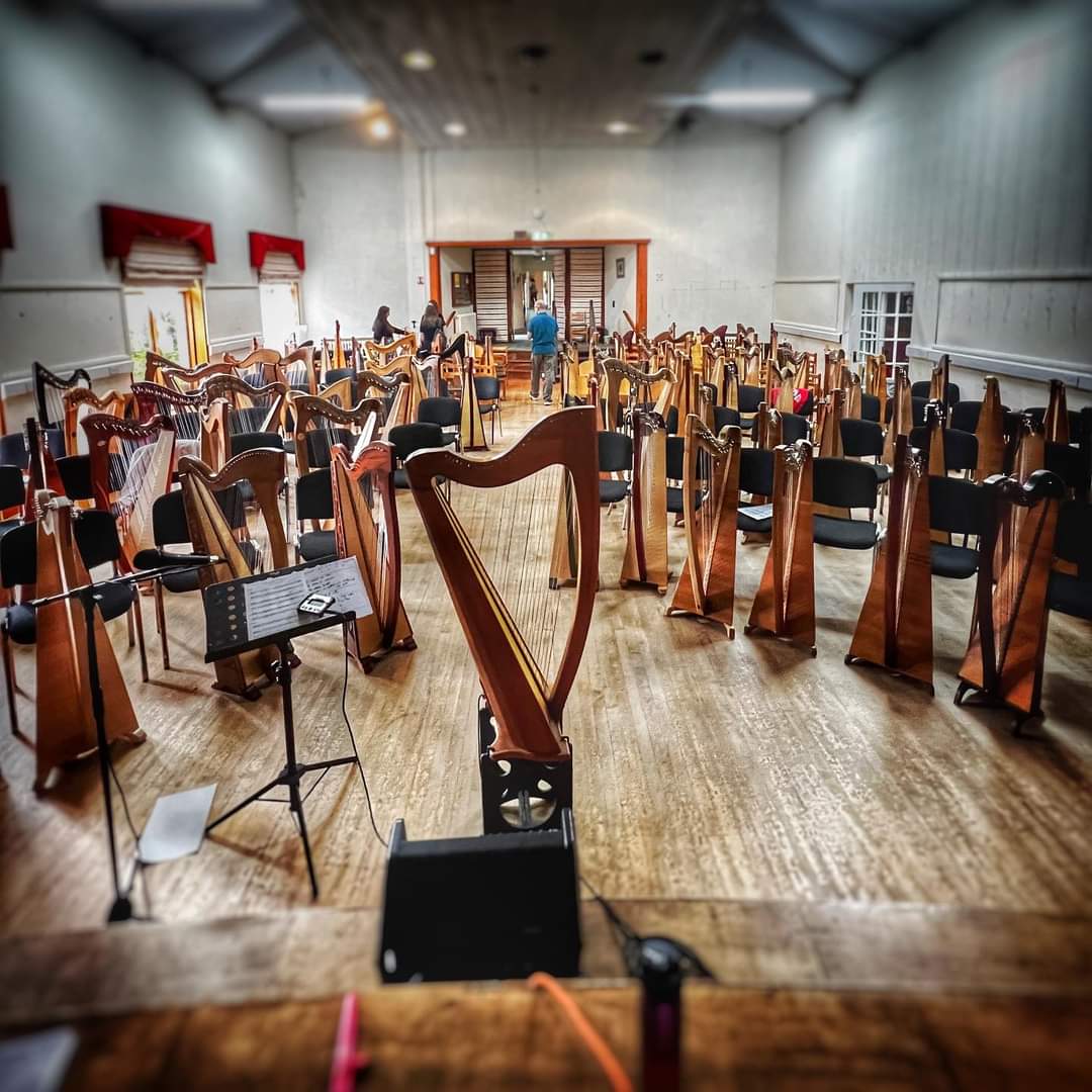 An empty hall of people with lines of harps in front of empty chairs