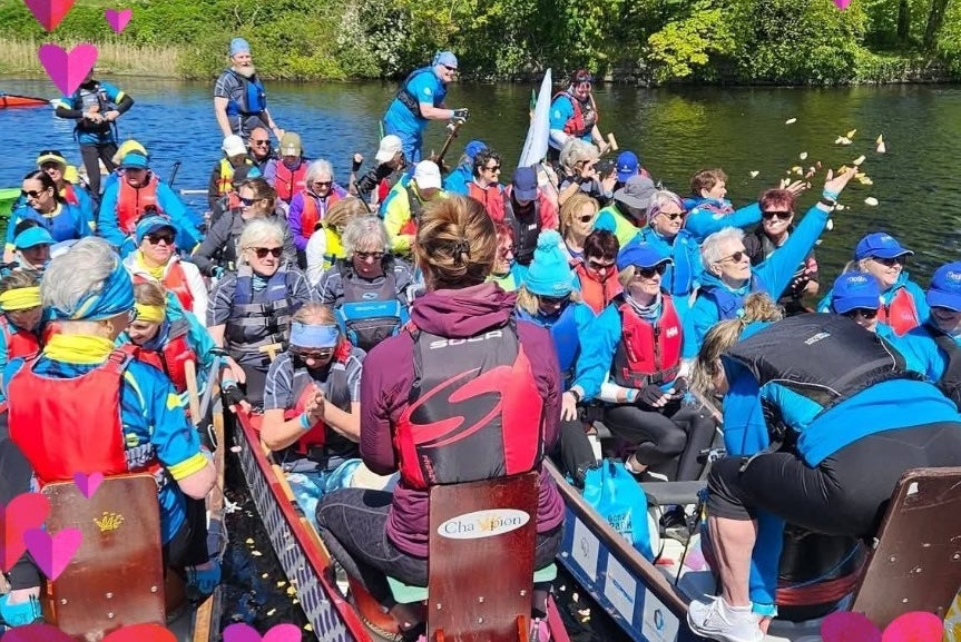 Groups of people in long canoe type boats all lined up tightly together on water. Flower Ceremony celebrating life, casting thousands of petals in the air in unison