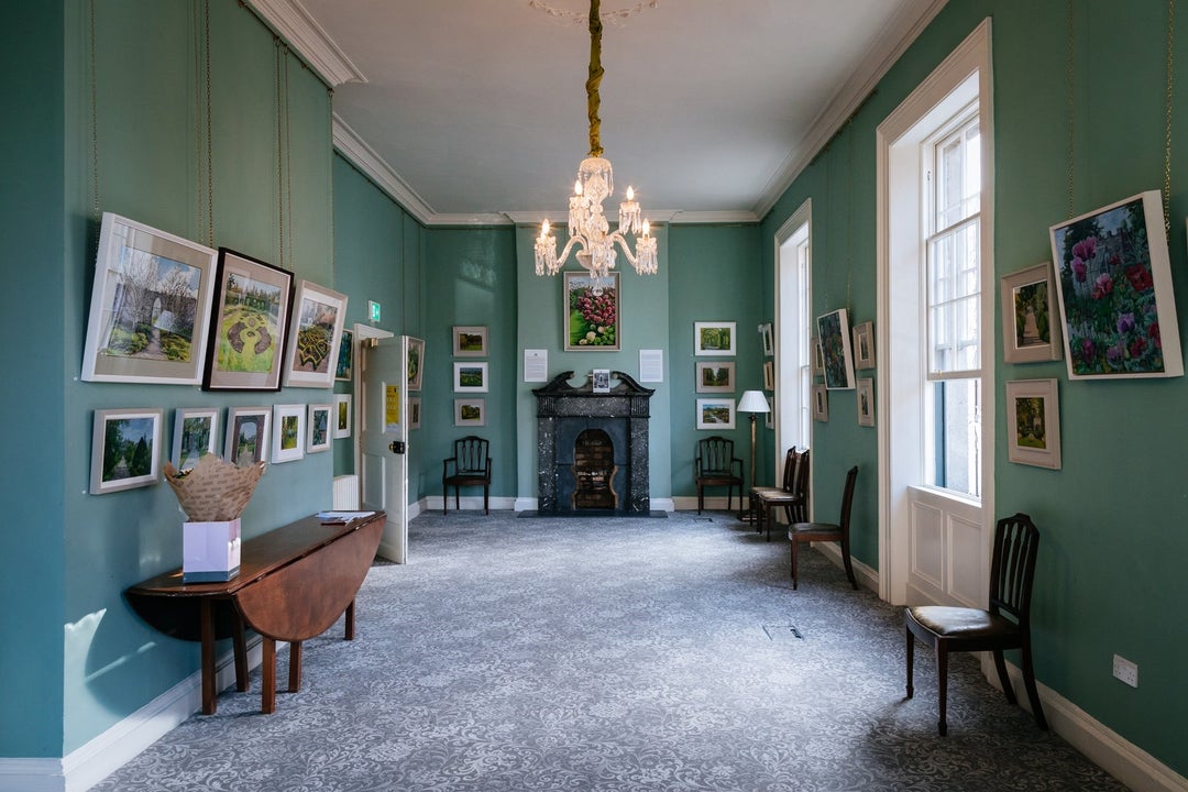 A large room with antique furnishings and décor with an ornate fire place at the top of the room