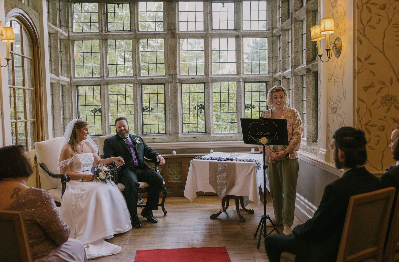 Bride and groom sitting as a celebrant speaks to seated guests