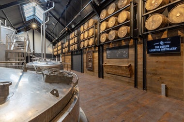 A room in a distillery with shelves lined with wooden whiskey barrels