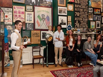 Guide leading a small group tour in a room full of memorabilia