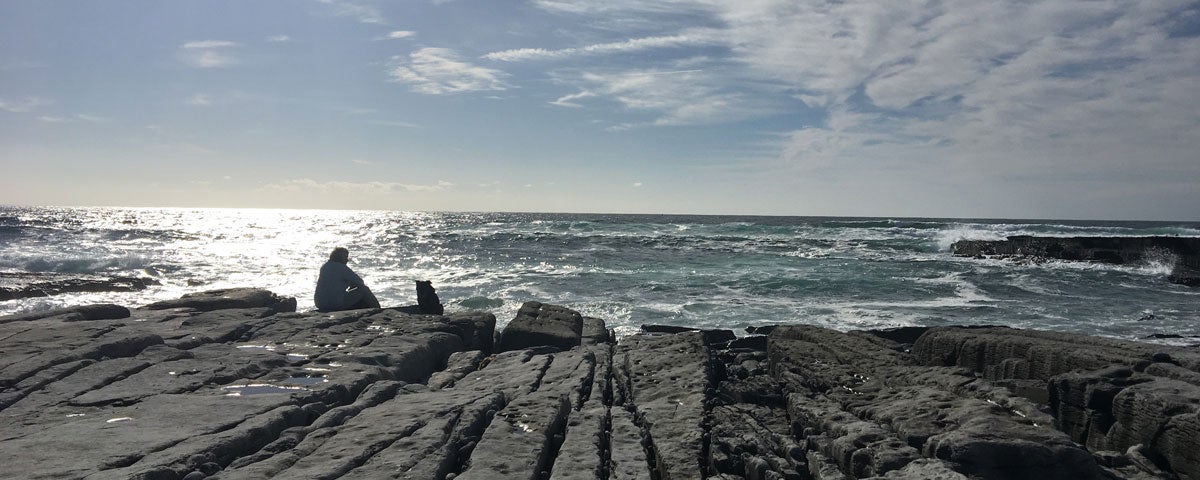 A person sitting on rocks looking out at the sea