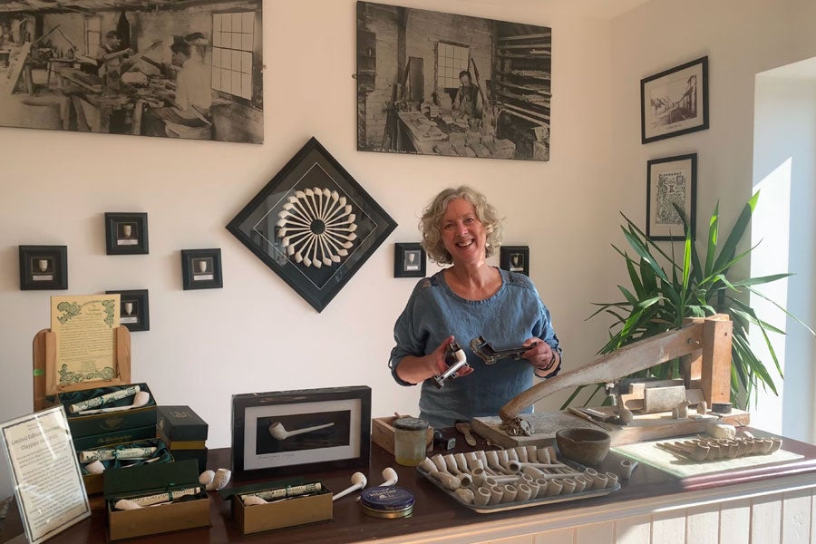 A large selection of clay pipes on display on the counter and the wall