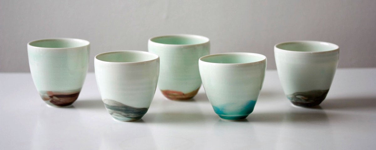 Five handcrafted espresso cups all white with different colours on the bottom of them