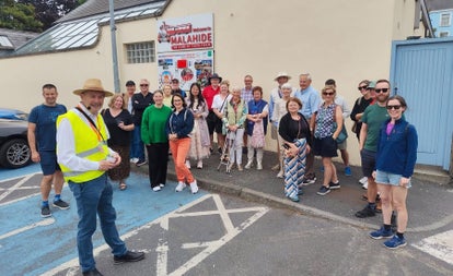 A group of people standing and their tour guide with Malahide Historical Tours