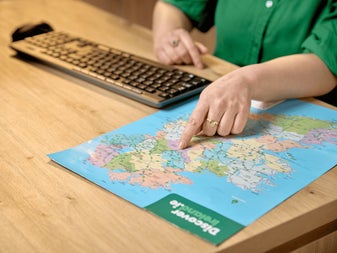 A genealogy researcher identifies an ancestral location on a map of Ireland. Consultations at the Irish Family History Centre help visitors connect family records with townlands, counties and ancestral homelands.
