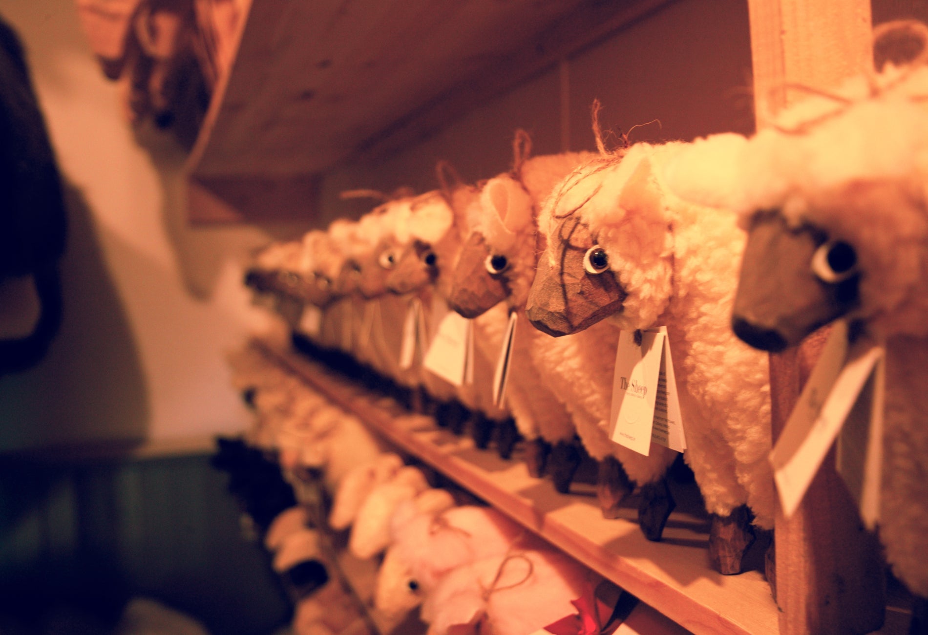 Two shelves with rows of wooden sheep with tags on them