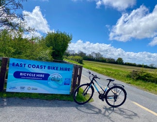The sign for East Coast Bike Hire and a bike at a road side gateway