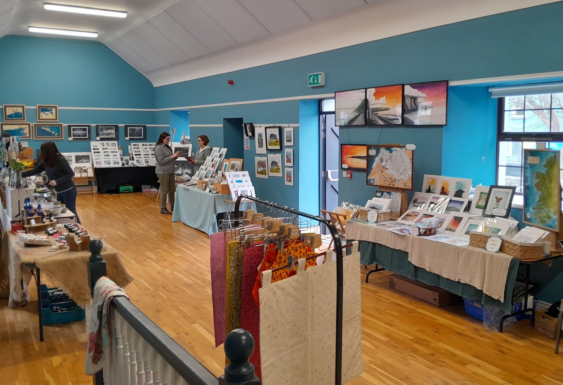 Room with blue walls and a wooden floor with tables displaying products all around