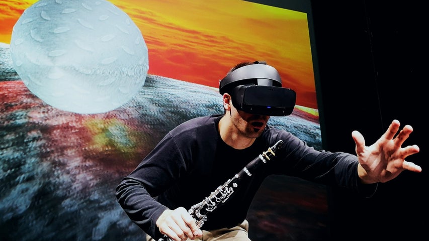 Music Current 2026 _ Ressi Benes, a man wearing a VR headset and holding a clarinet is reaching out with his other hand.