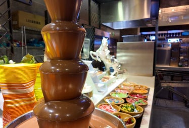Chocolate fountain with various salads in bowls in the background