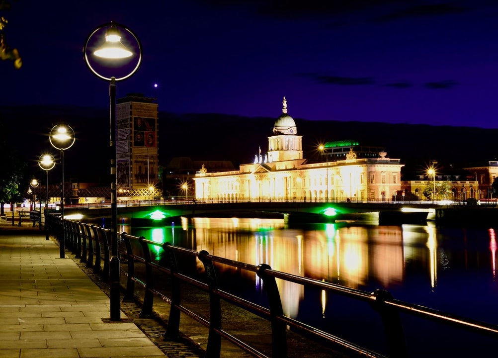 Riverside walkway at night with a building lit up in the background