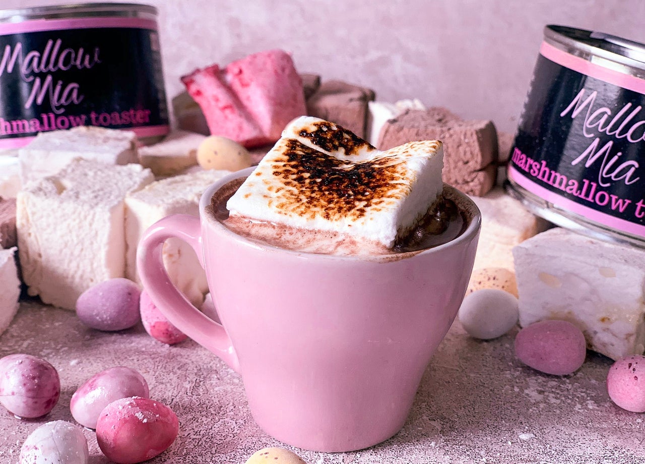 Marshmallow sitting on top of drinking chocolate in a pink mug surrounded by other pink items