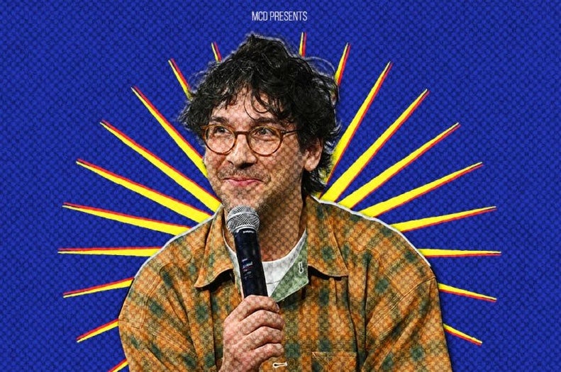 American comedian and writer, Rick Glassman - a smirking man holding a mic up to his chin.