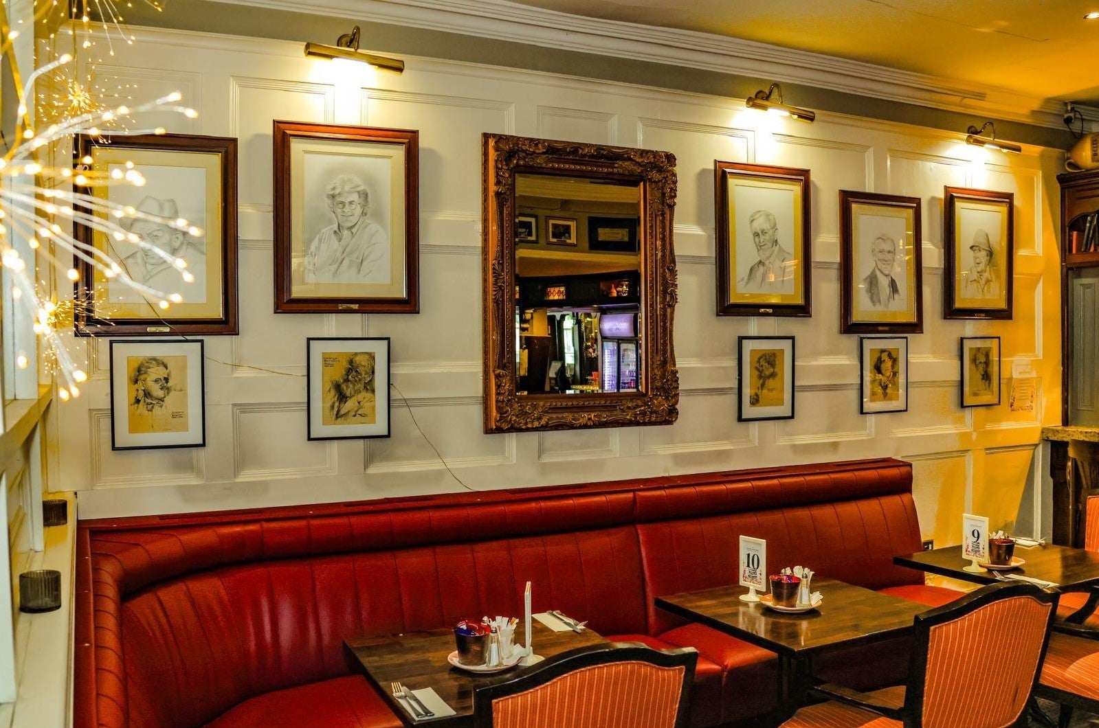 Red seat with tables set for services and pictures and a mirror on the wall above