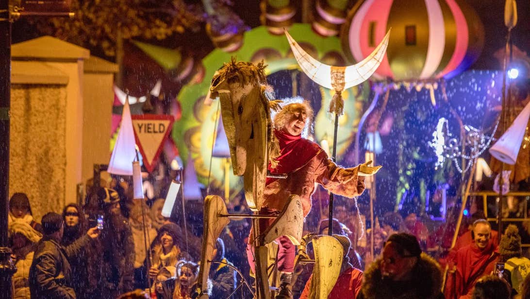 The Samhain Procession at Púca Festival with a man rising a wooden horse and other floats behind him.