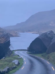Road leading to the sea with large rocks either side and mountains in the background