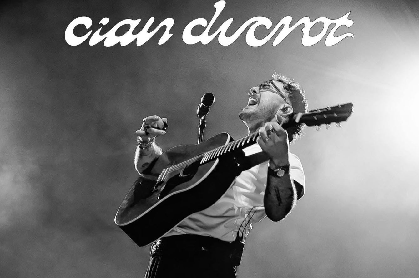 A man with a guitar performing with head thrown back, singing.