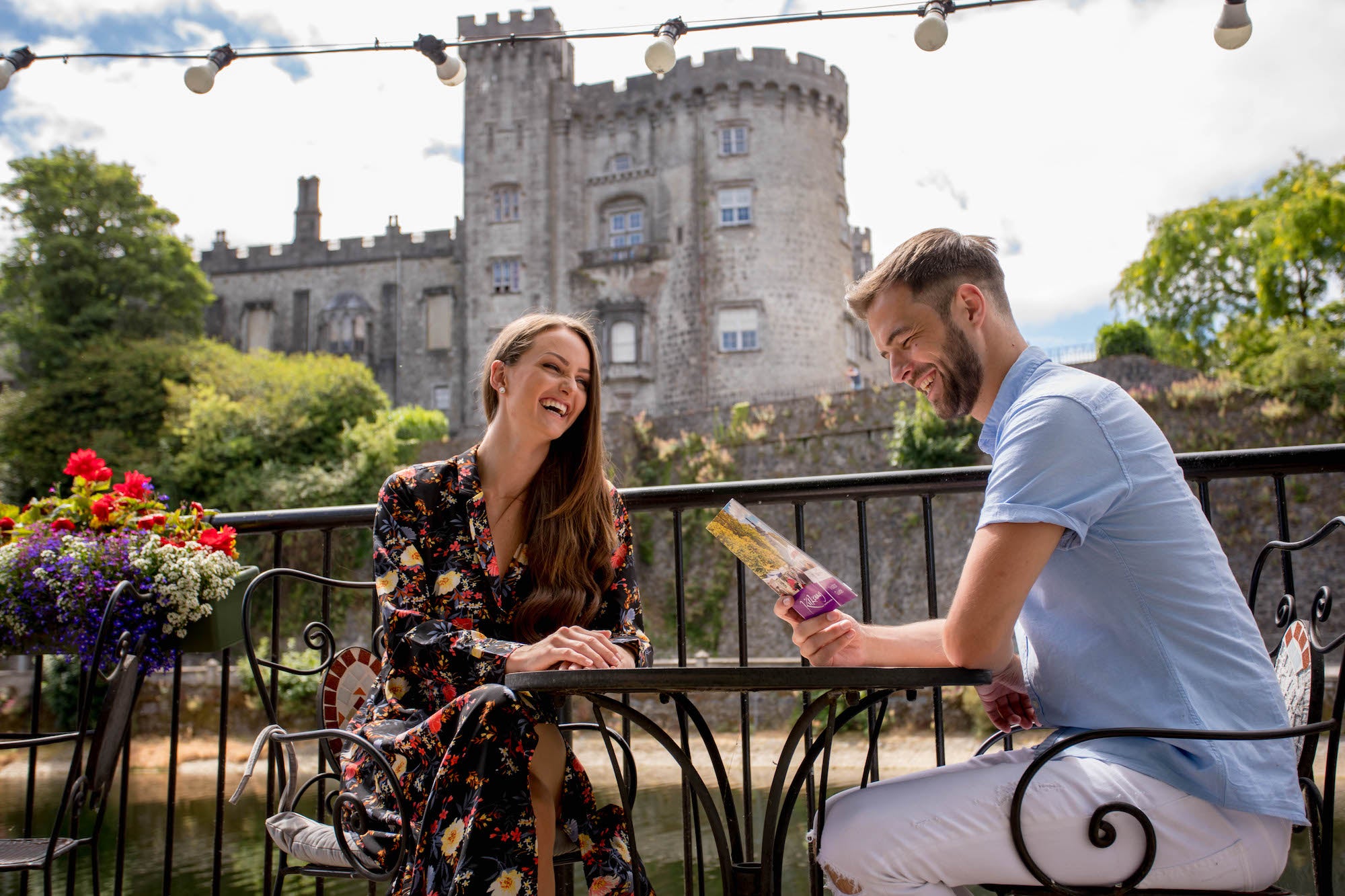 A couple sitting at a table with Kilkenny Castle in the background in County Kilkenny.