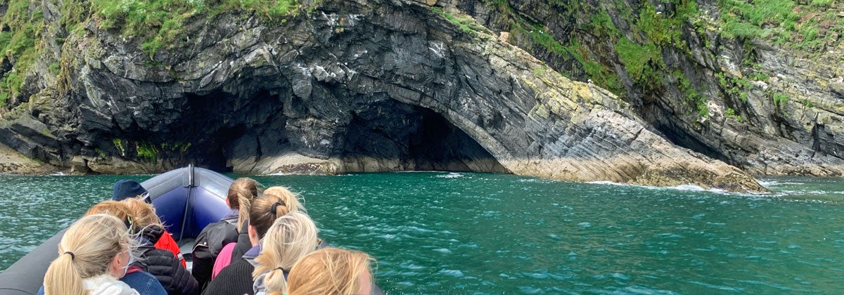 People on a boat on the sea going towards a sea cave