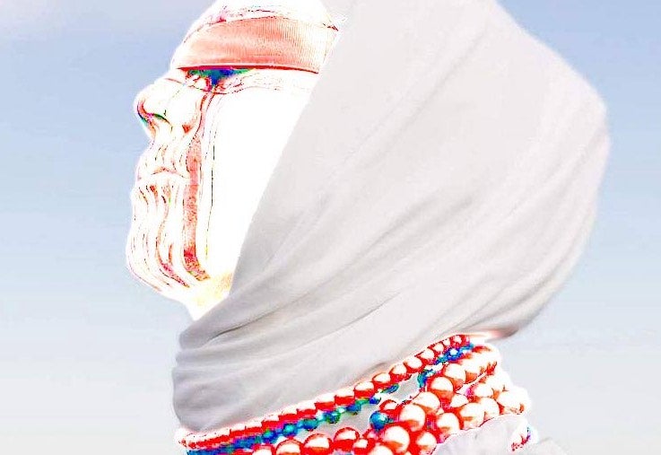 Viktoria Kondratieva wearing a headscarf, blindfold, bead necklaces and red and white make-up.