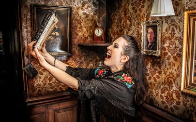 A witch holds up a book of spells in the air while laughing