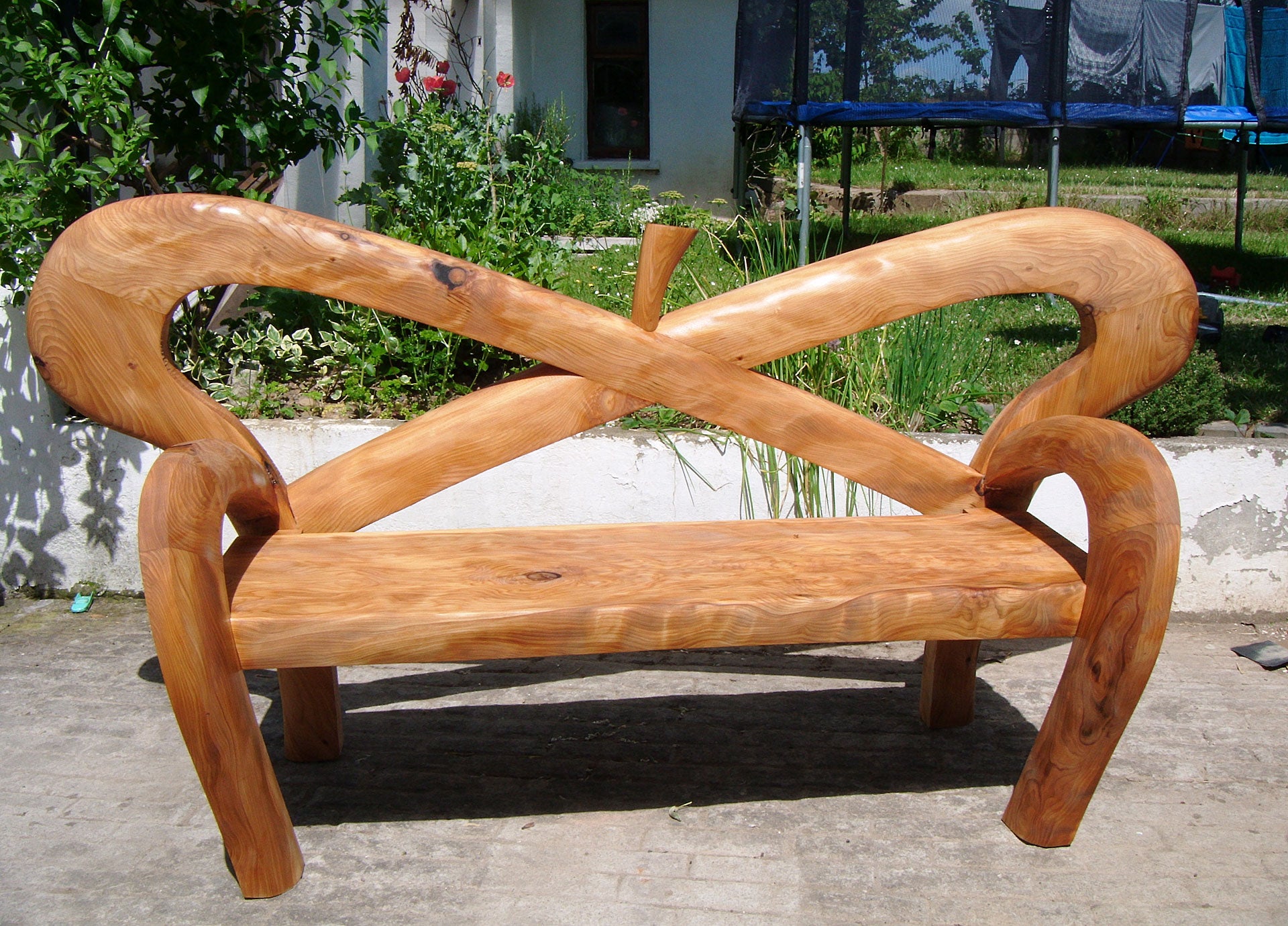 Architectural Furniture wooden garden bench with curved lines crossing in back