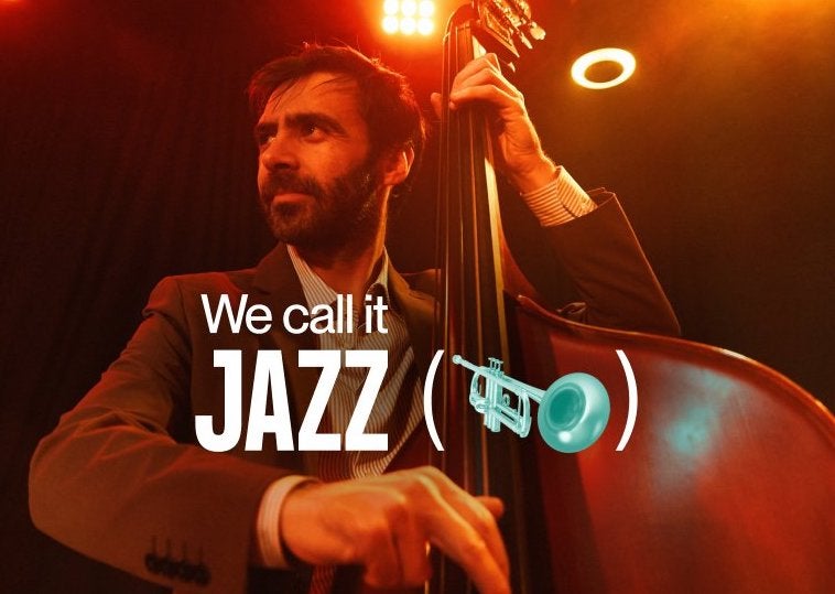 A man in jacket and shirt is playing a double bass, looking way to his right with spotlights behind.