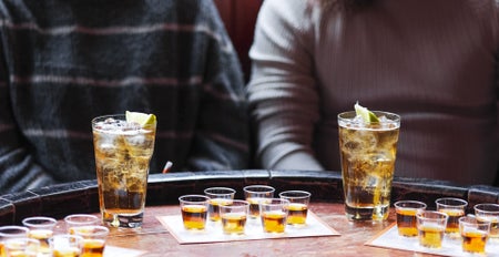 Two people sitting in front of a whiskey tasting table with a selection of glasses