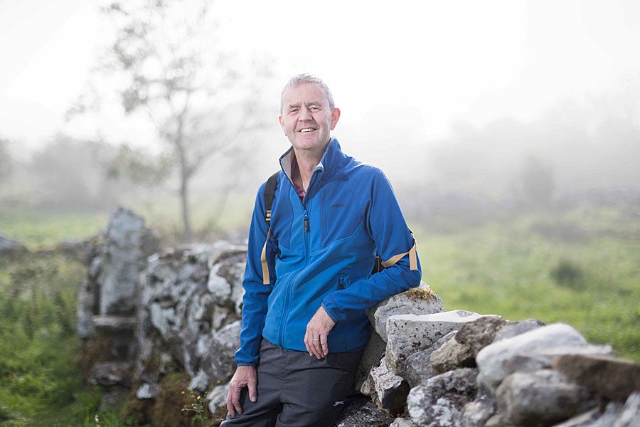 Pius Murray of Walk with Pius against a stone wall