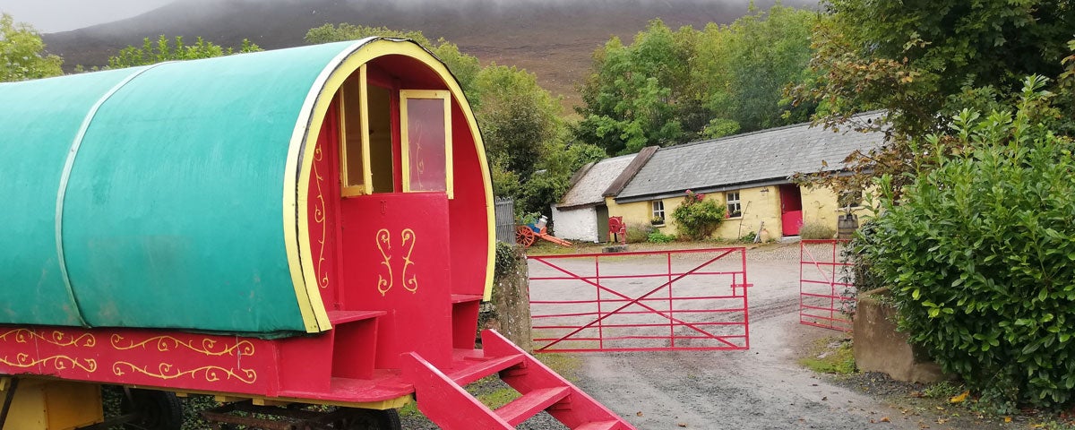Old style horse drawn caravan by an old fashioned farmhouse