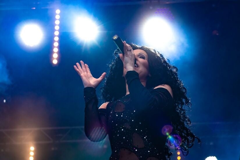 Viewed from below looking upwards at woman singing with spotlights behind.