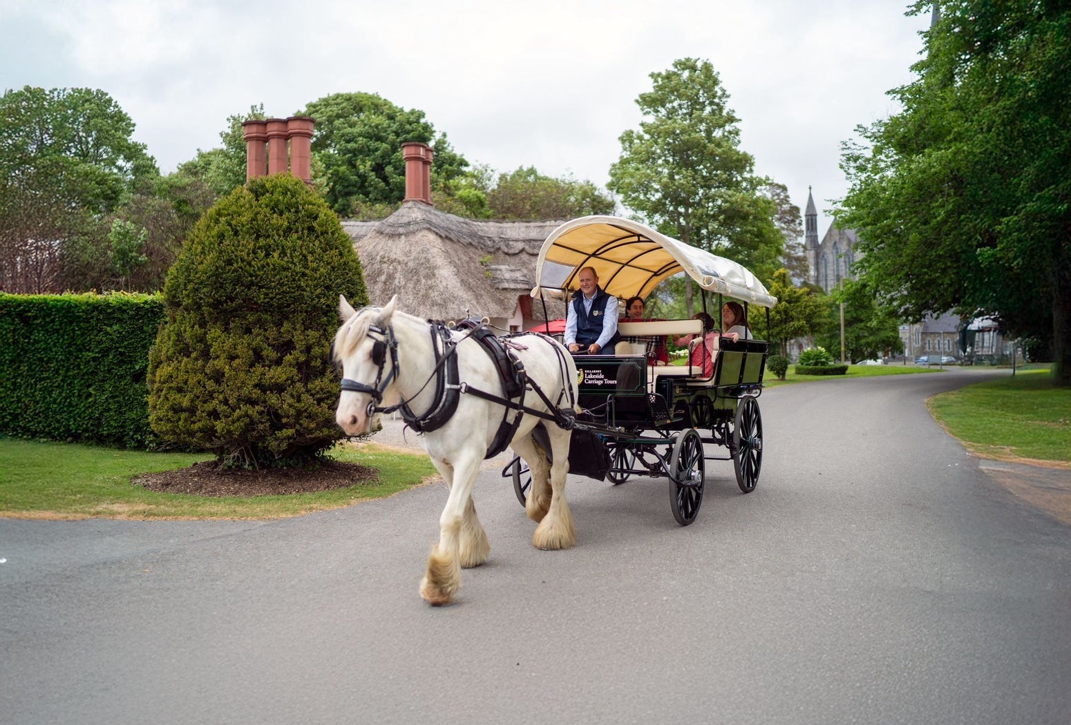 A horse drawn carriage and passengers moving down a village street