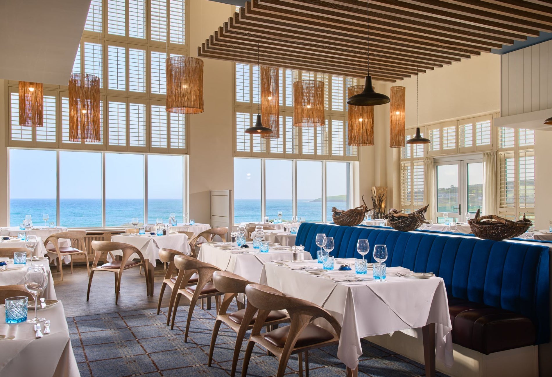 Bright coastal restaurant interior with sea views white clothed tables and blue seating