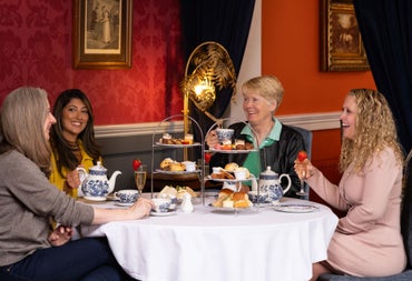 Guests enjoying afternoon tea with sandwiches pastries and hot drinks in an elegant restaurant setting