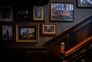 Traditional pub staircase with framed vintage photographs displayed on dark wood panelled walls